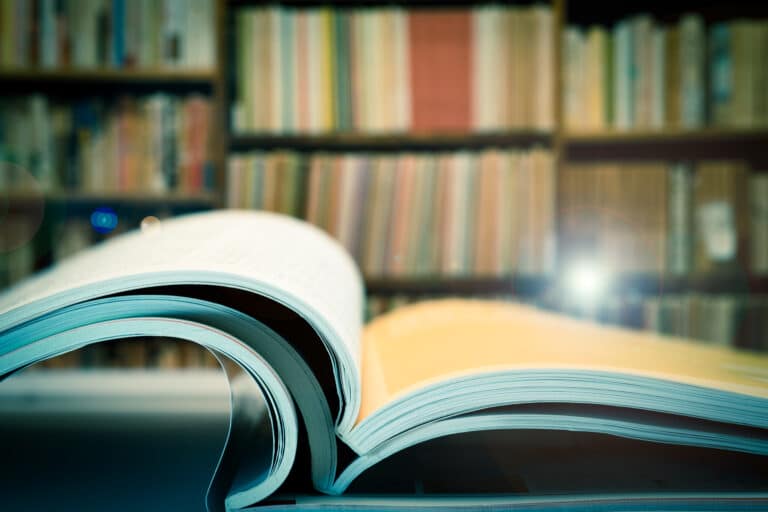 Piles of books and magazines on background of book shelf